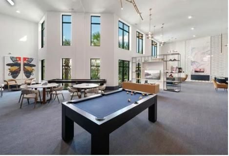 Residents' clubhouse lounge with a pool table and full-height windows