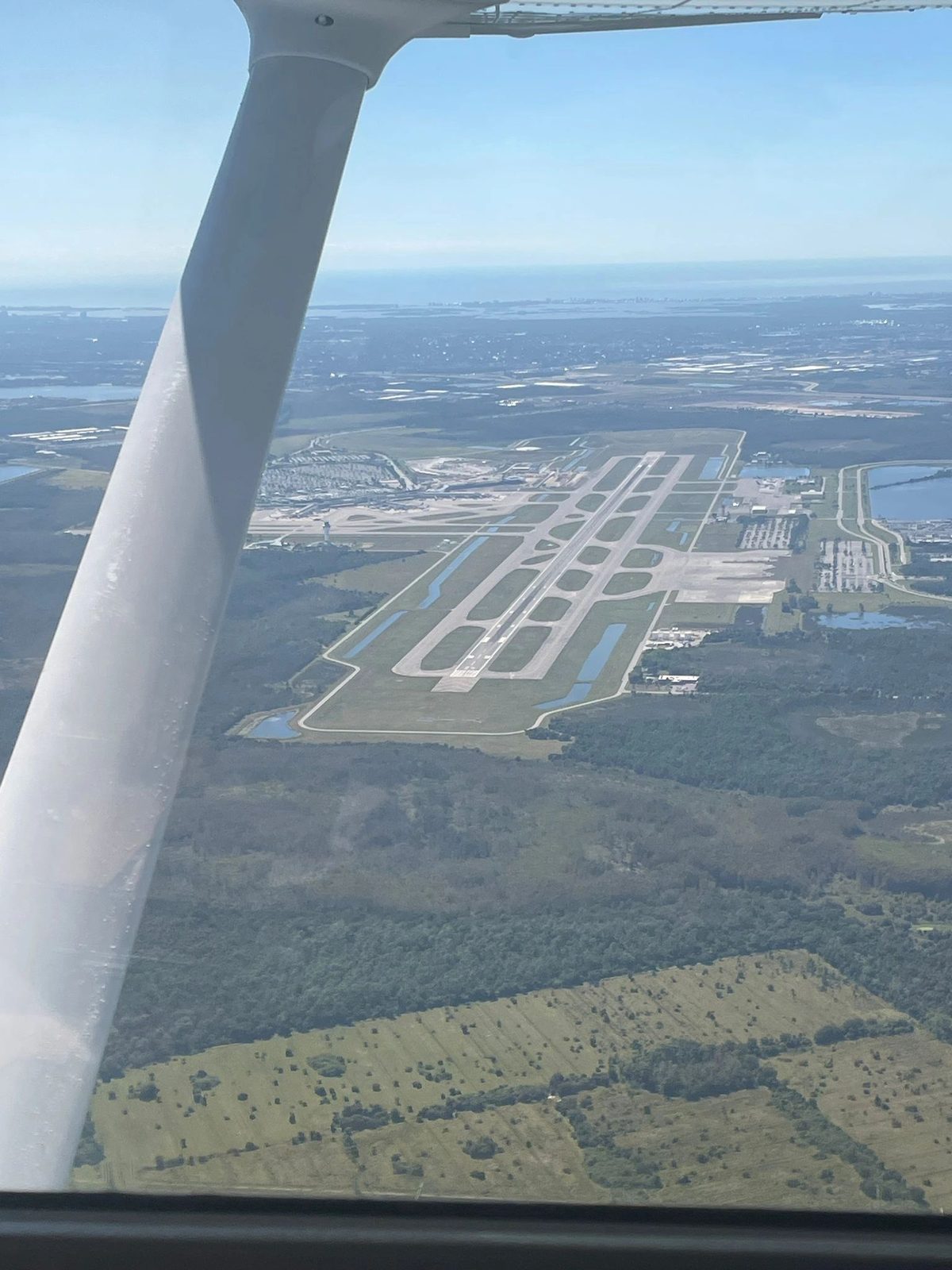 Airport runways from the air, seen past the wing strut of a training aircraft