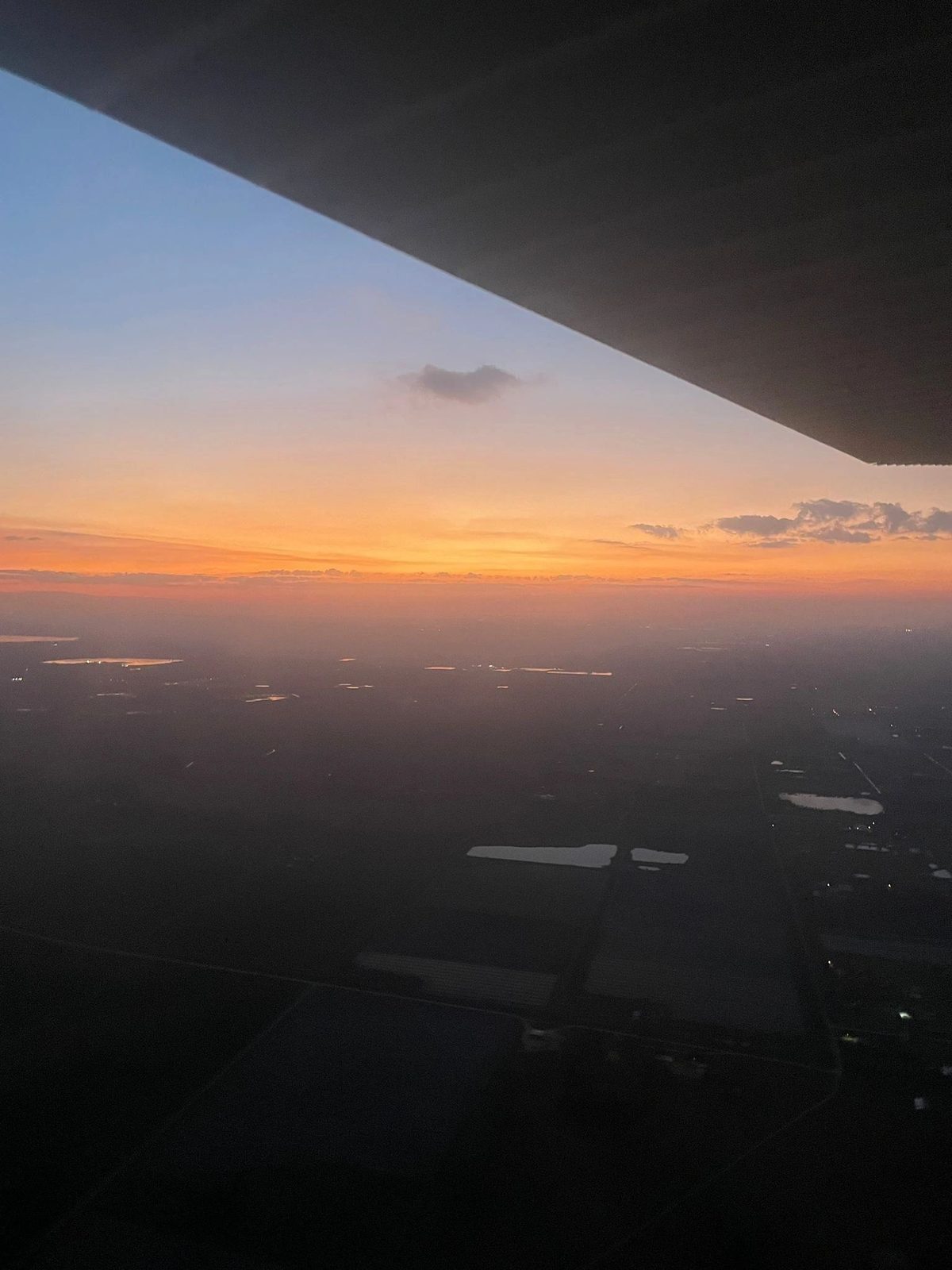 An aircraft wing silhouetted against the sunset at altitude